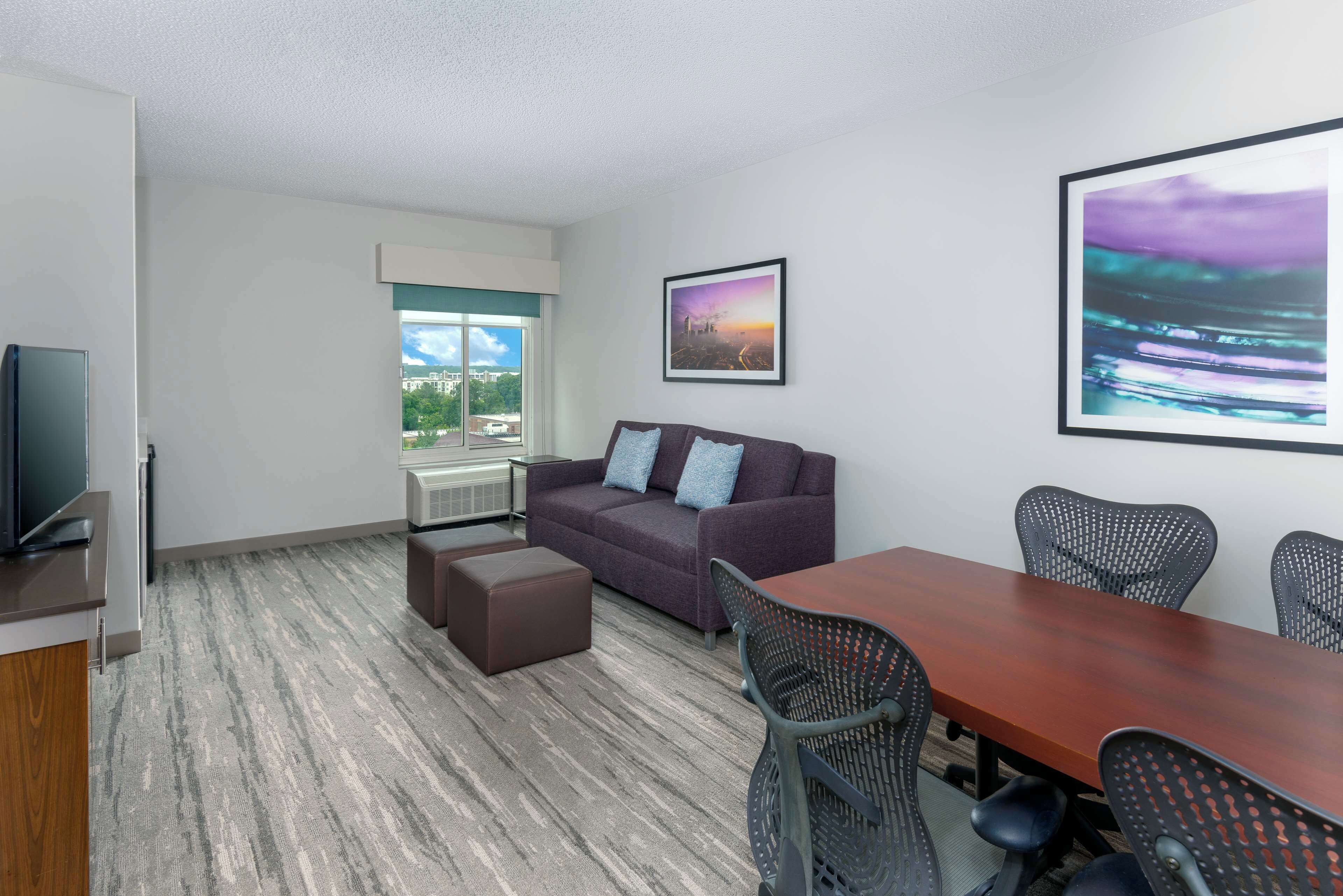 A modern conference room with a large table, several chairs, a sofa, and a television.