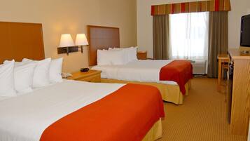 A hotel room with two beds, a desk, a chair, and a television.