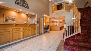 A hotel lobby with a reception desk, a staircase, and a dining area.