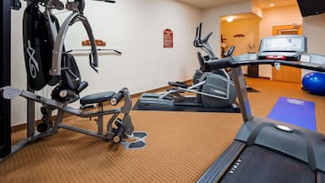 Un gimnasio con máquinas de cardio, máquinas de pesas y una cinta de correr.