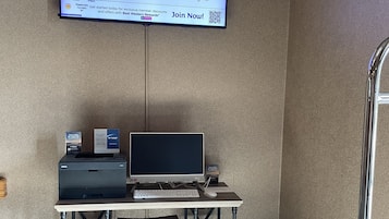 Habitación de hotel con escritorio, computadora y televisor de pantalla plana mostrando un programa de recompensas.