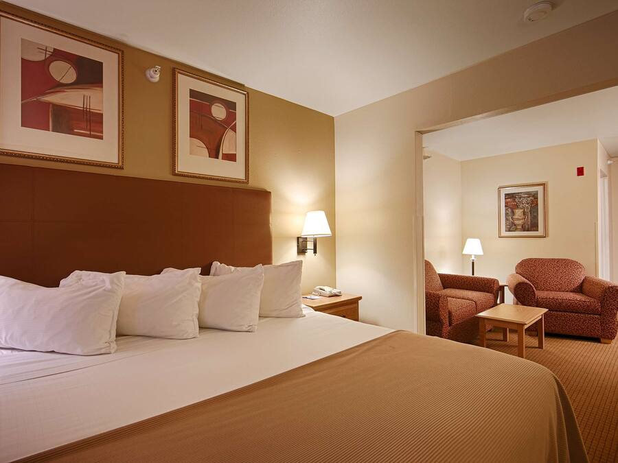 Ett hotellrum med en stor säng, två stolar, ett litet bord och två vägglampor.