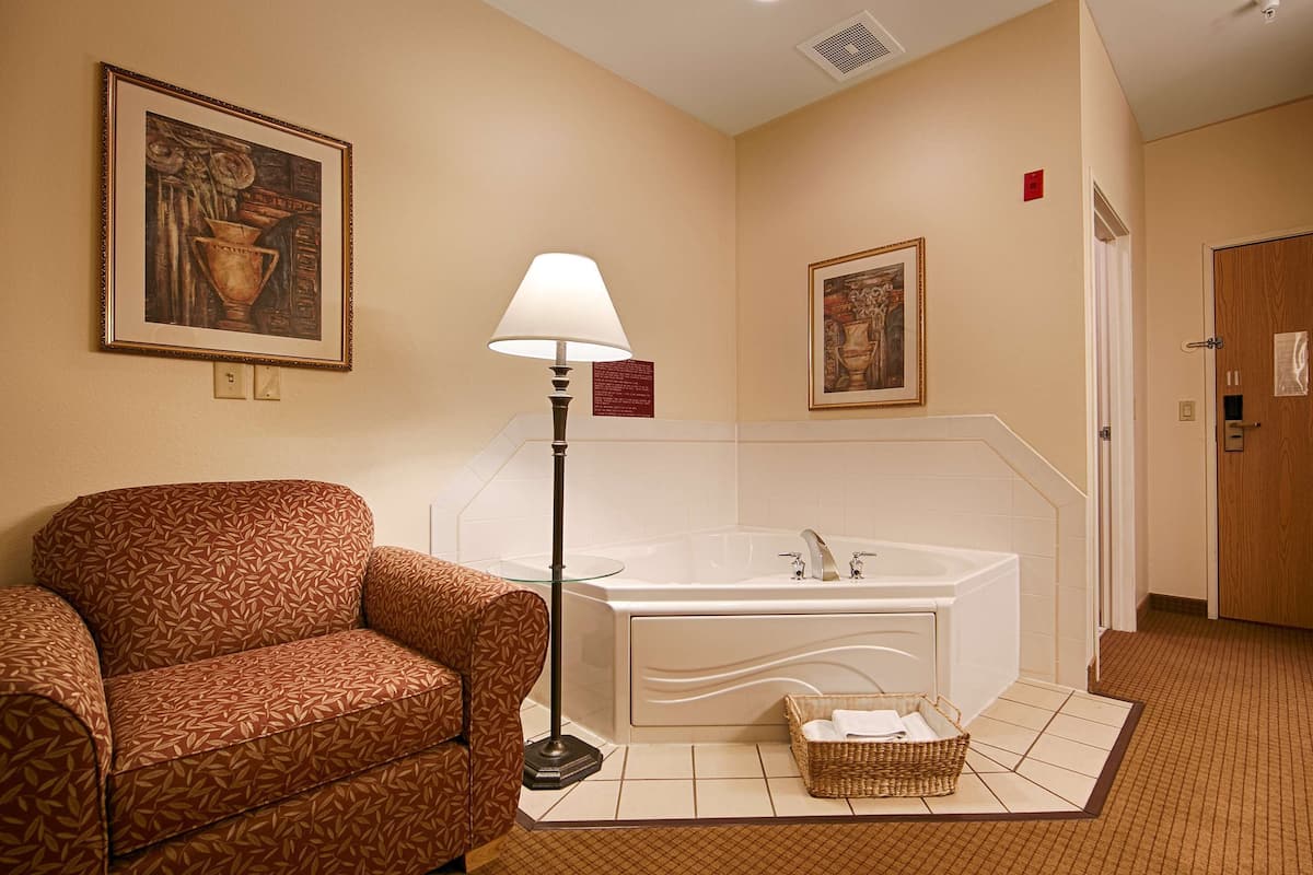 Un baño de hotel con sofá, lámpara de pie, bañera y dos cuadros en la pared.
