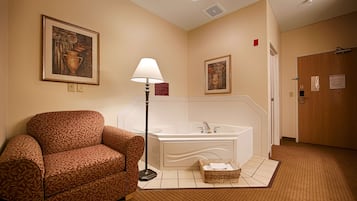 Un baño de hotel con sofá, lámpara de pie, bañera y dos cuadros en la pared.