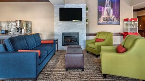 A modern living room with a fireplace, a flat-screen TV, and a dining area with a bar. - Comfort Inn & Suites Cincinnati Uptown Clifton (Cincinnati)