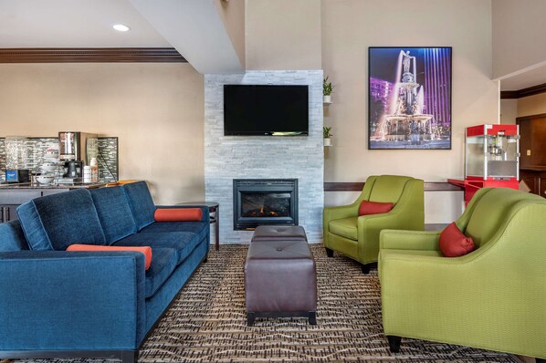 A modern living room with a fireplace, a flat-screen TV, and a dining area with a bar. - Comfort Inn & Suites Cincinnati Uptown Clifton (Cincinnati)