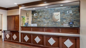 A reception area with a stone wall, a wooden reception desk, and a digital kiosk. - Comfort Inn & Suites Cincinnati Uptown Clifton (Cincinnati)