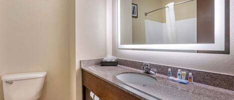 A bathroom with a toilet, sink, and mirror.