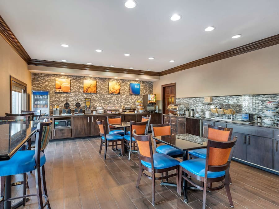 A modern restaurant with a bar area, wooden flooring, and blue cushioned chairs.