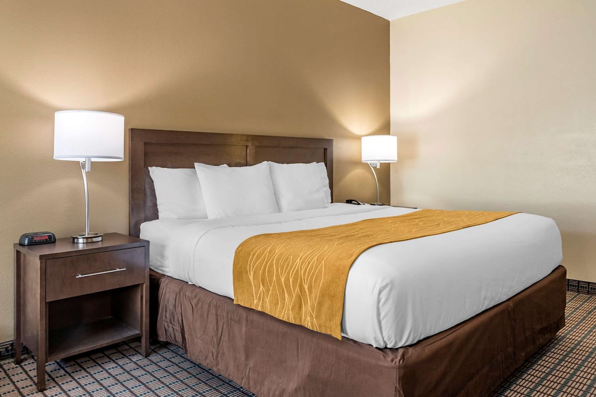 A hotel room with a large bed, two bedside tables, and a nightstand.