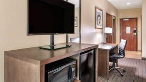 A hotel room with a flat-screen TV, a desk with a chair, a microwave, and a refrigerator. - Comfort Inn & Suites Cincinnati Uptown Clifton (Cincinnati)