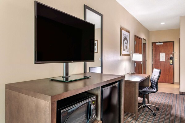 A hotel room with a flat-screen TV, a desk with a chair, a microwave, and a refrigerator. - Comfort Inn & Suites Cincinnati Uptown Clifton (Cincinnati)