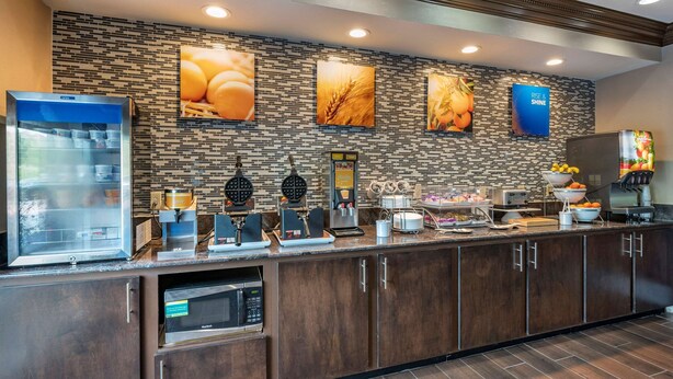 A breakfast bar with a self-serve coffee station, a refrigerated display case, and a microwave. - Comfort Inn & Suites Cincinnati Uptown Clifton (Cincinnati)