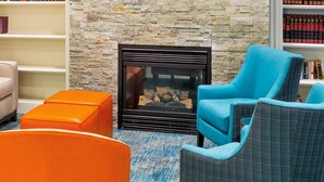 A cozy seating area with a stone wall, a fireplace, and bookshelves.