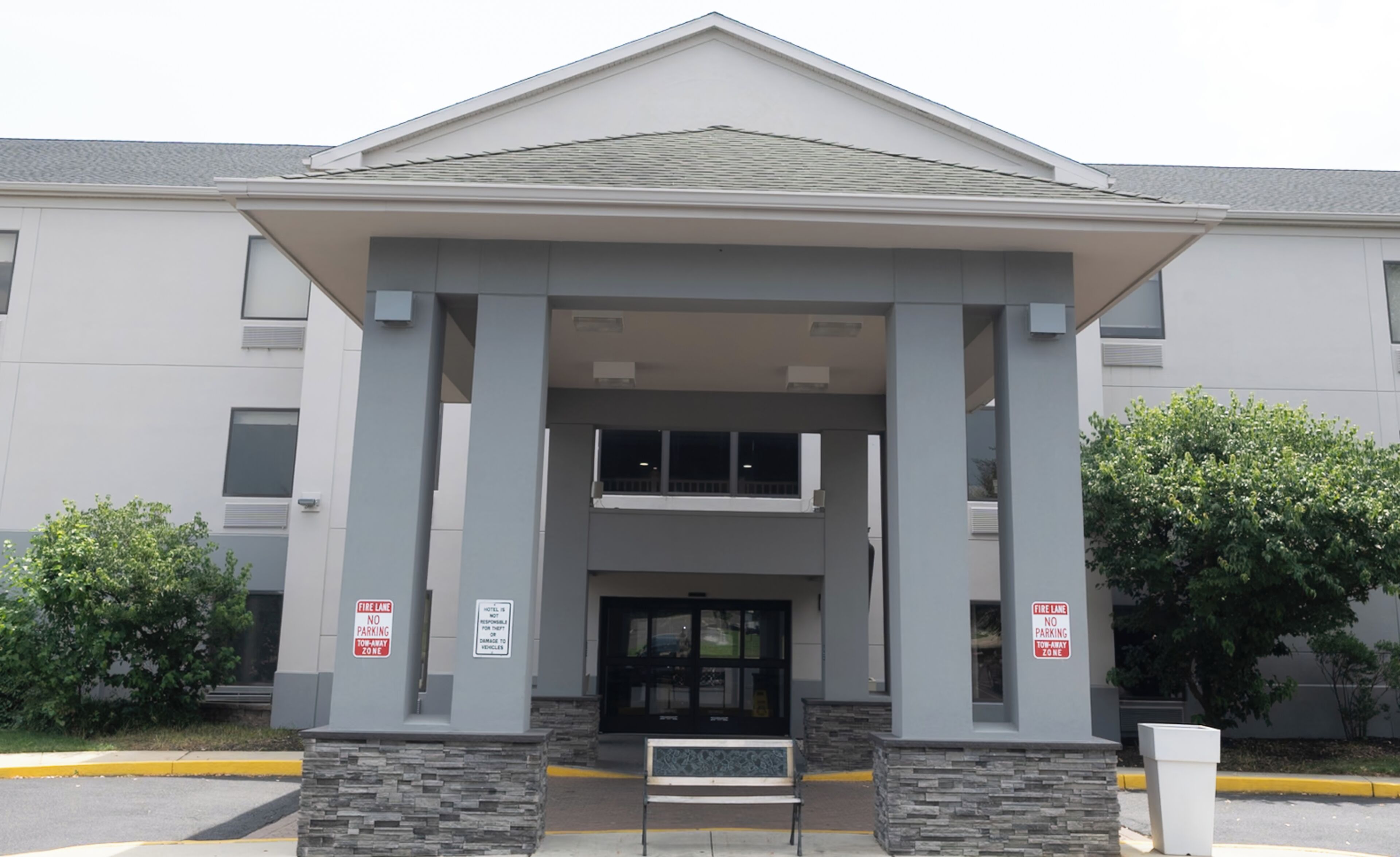 A building with a modern architectural design, featuring a prominent entrance with columns and a flat roof. There are signs indicating a fire lane and no parking zones.