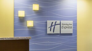 A Holiday Inn Express reception desk with a blue patterned wall and three illuminated square signs.