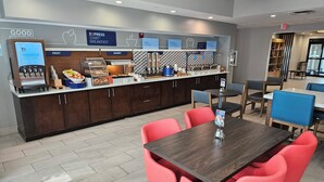 Un espace dédié au petit-déjeuner, équipé d'une machine à café, d'un présentoir de fruits et d'un assortiment de produits de boulangerie.