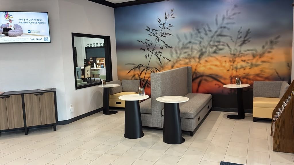 A modern interior with a sofa, two round tables, a coffee station, and a wall-mounted TV.