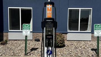 An electric vehicle charging station with a sign indicating it is for EV charging only, located in front of a building with windows and a brick wall.