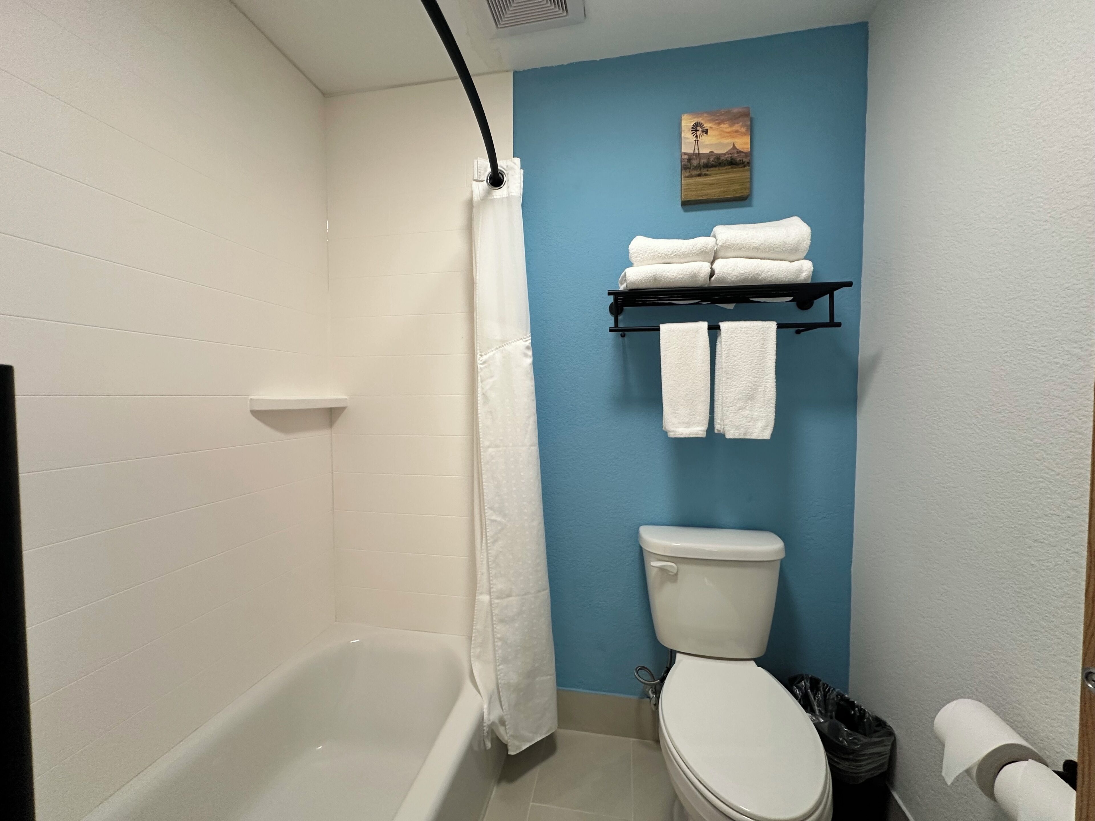 A bathroom with a bathtub, toilet, and a towel rack with towels.