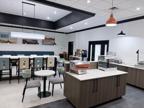 Un café moderno con una isla central, zona de estar y una barra con una máquina de café.
