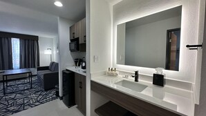 A hotel room with a modern bathroom, a dining area, and a living room.