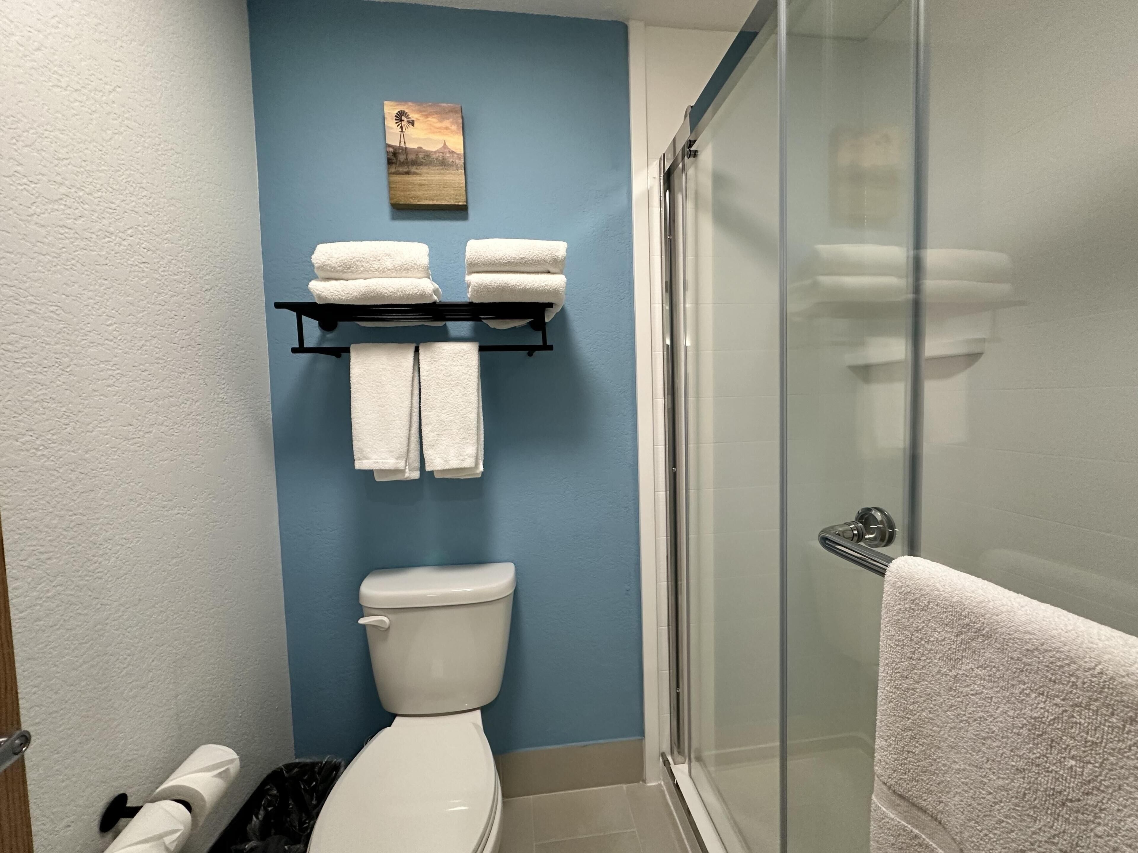 Une salle de bain équipée de toilettes, d’une douche à parois de verre et d’un porte-serviettes avec des serviettes.