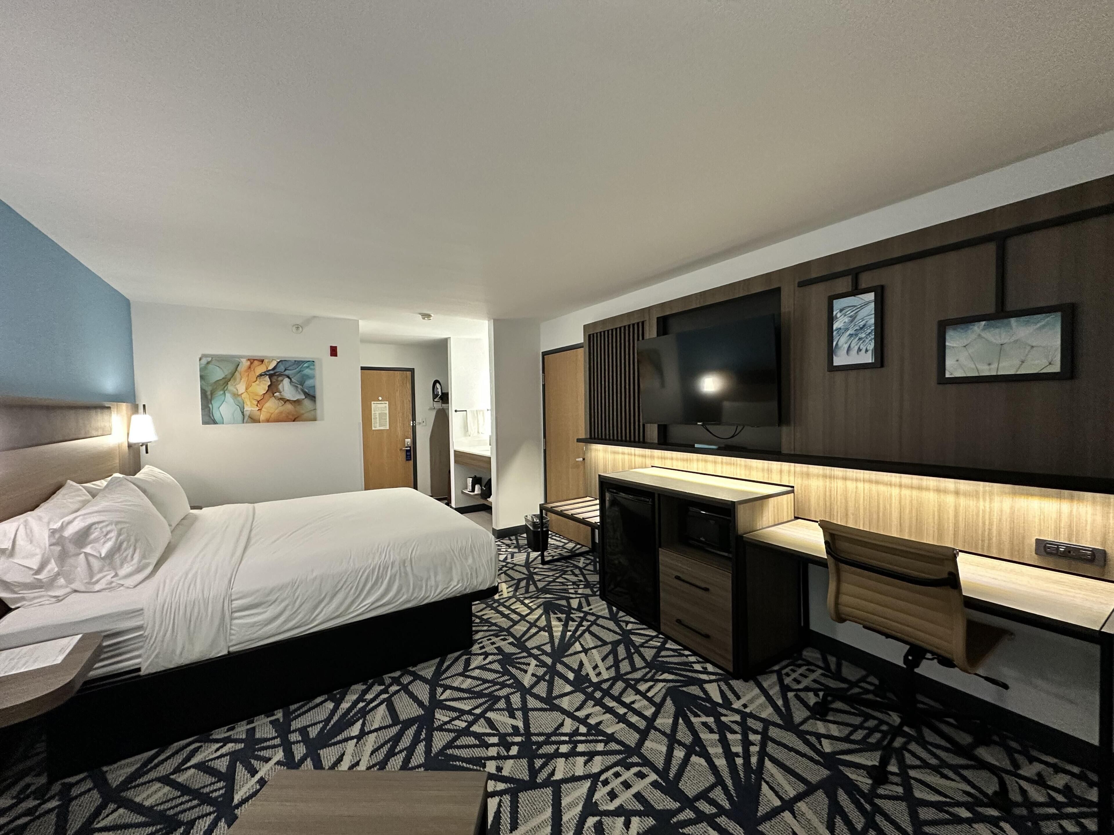 Une chambre d’hôtel équipée d’un lit, d’un bureau, d’une télévision et d’œuvres d’art.