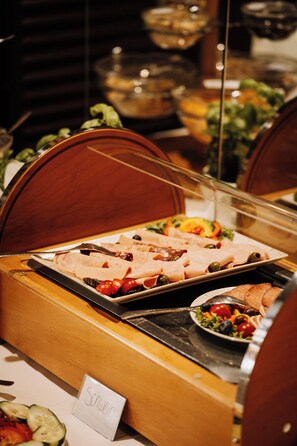 A buffet setup with various food items, including meats, cheeses, and vegetables, with a sign indicating 'Schwein' on the table. - Hotel Central (Willingen)