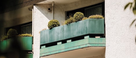 A multi-story building with balconies, each with a small round garden.