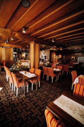 Un restaurante con vigas de techo de madera, sillas a rayas y suelo estampado.
