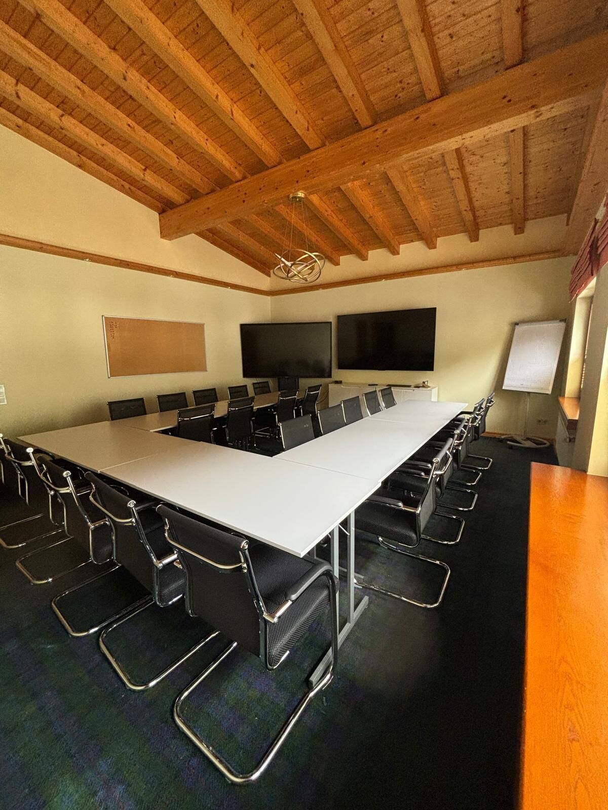 Une salle de conférence équipée d’une longue table, de nombreuses chaises, d’un écran de projection et d’un tableau blanc.
