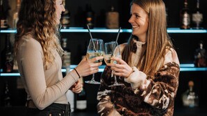 Two people at a bar with shelves of bottles in the background. - Hotel Central (Willingen)