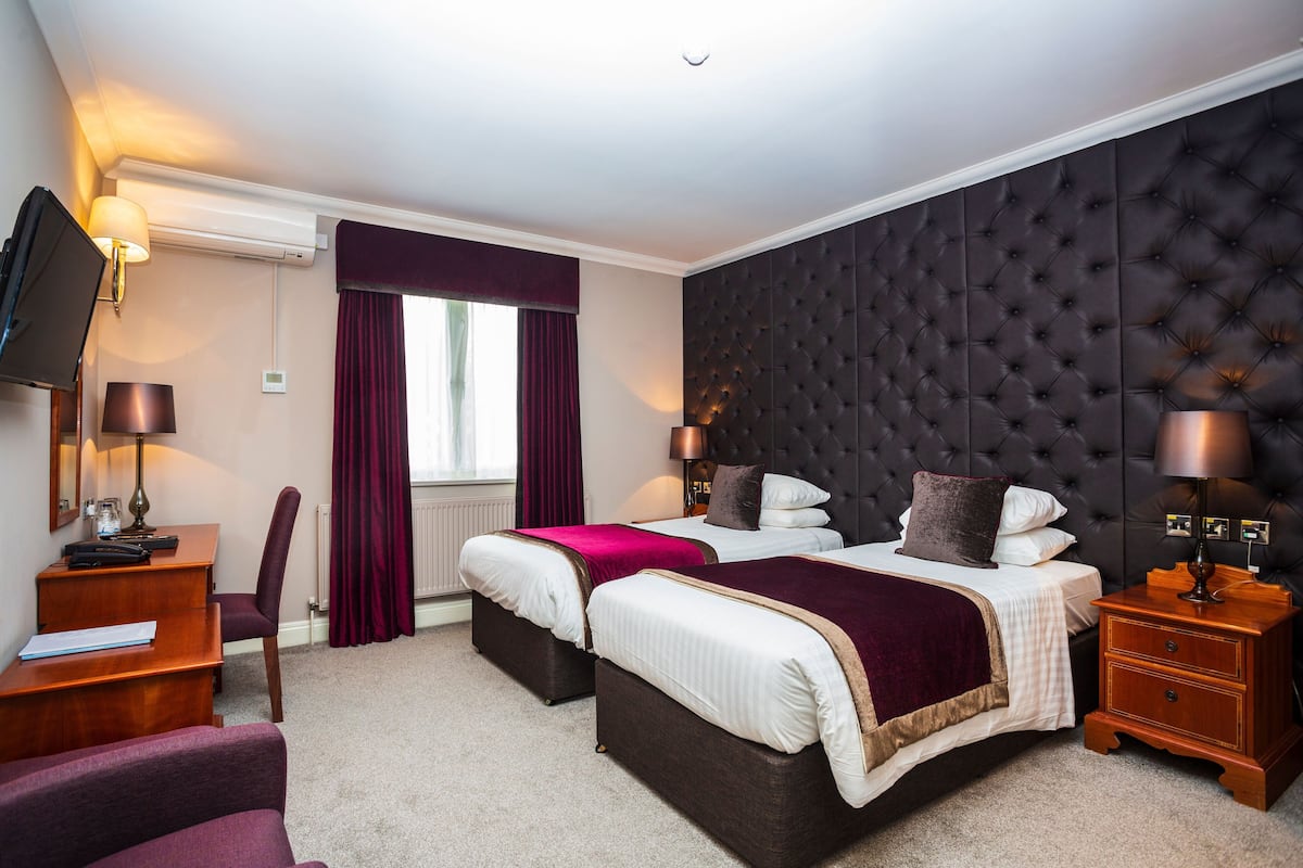A hotel room with two beds, a TV, a desk, and a chair.