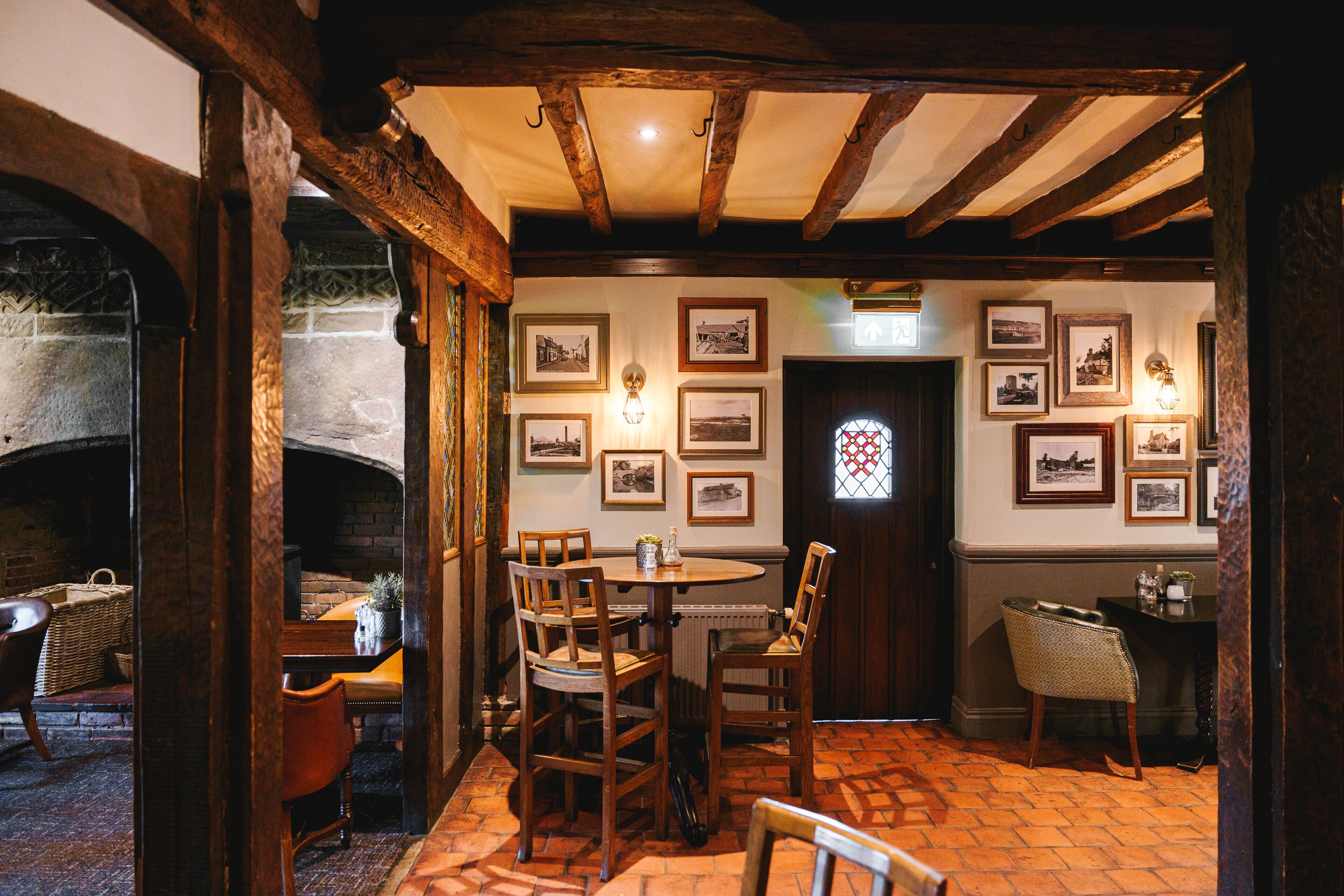 A cozy dining area with wooden chairs, a round table, and a brick fireplace.