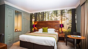 A hotel room with a large bed, a nightstand, a chair, and a small table. - The Moat House (Stafford)