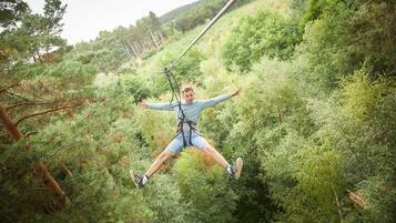 A person bungee jumping from a high point surrounded by dense green foliage.