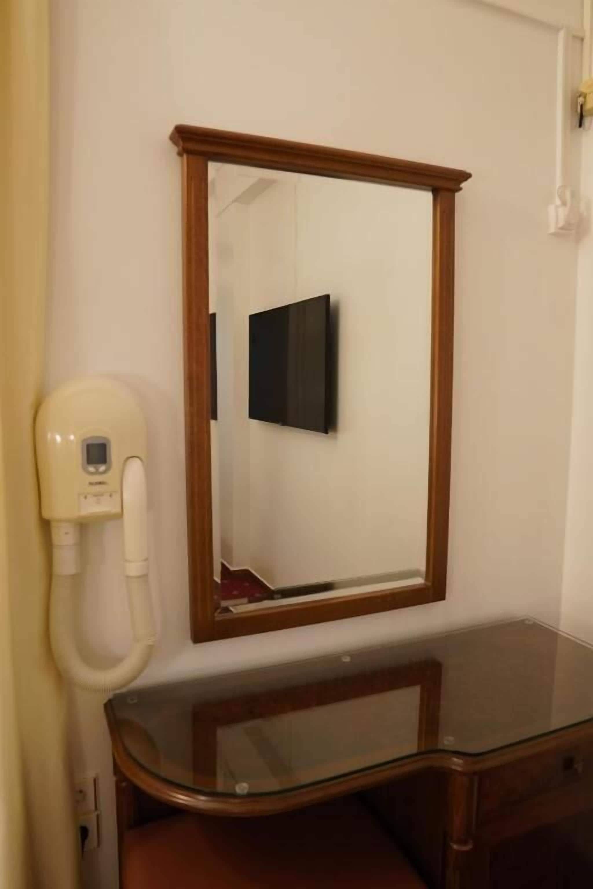 Ein Badezimmer mit einem spiegelnden Holzbettrahmen, einem Waschtisch aus Glas und einem an der Wand befestigten Fön.
