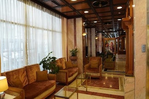 A lobby with a sofa, armchairs, a coffee table, and a potted plant.