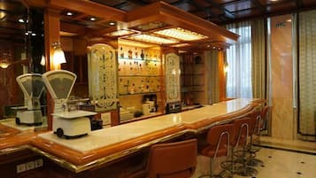 Una zona de bar con una barra larga, taburetes y una exhibición de botellas de licor.