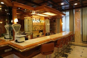 A bar area with a long counter, bar stools, and a display of liquor bottles.
