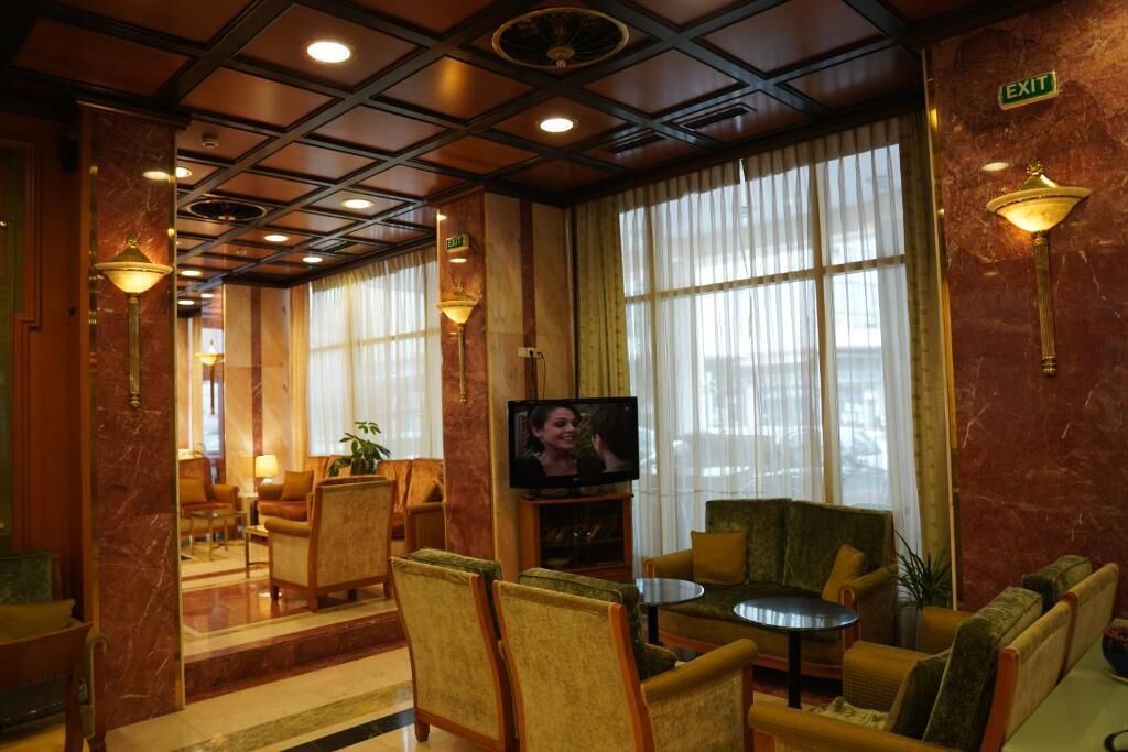 A hotel lobby with a television, seating area, and an exit sign.
