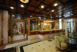 A lobby with a reception desk, seating area, and a painting on the wall. - Balasca Hotel (Athens)