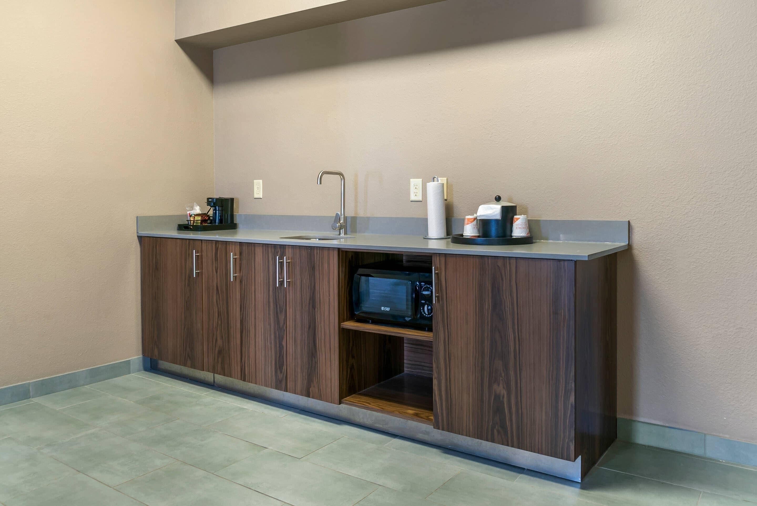 A kitchenette with a built-in microwave, a coffee maker, and a paper towel dispenser.