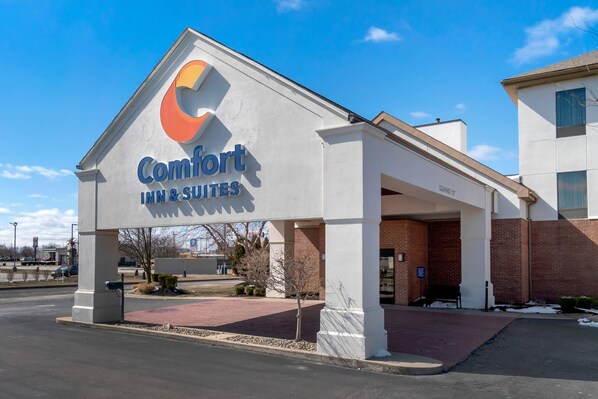 A Comfort Inn & Suites with a prominent sign, a covered entrance, and a brick building in the background.