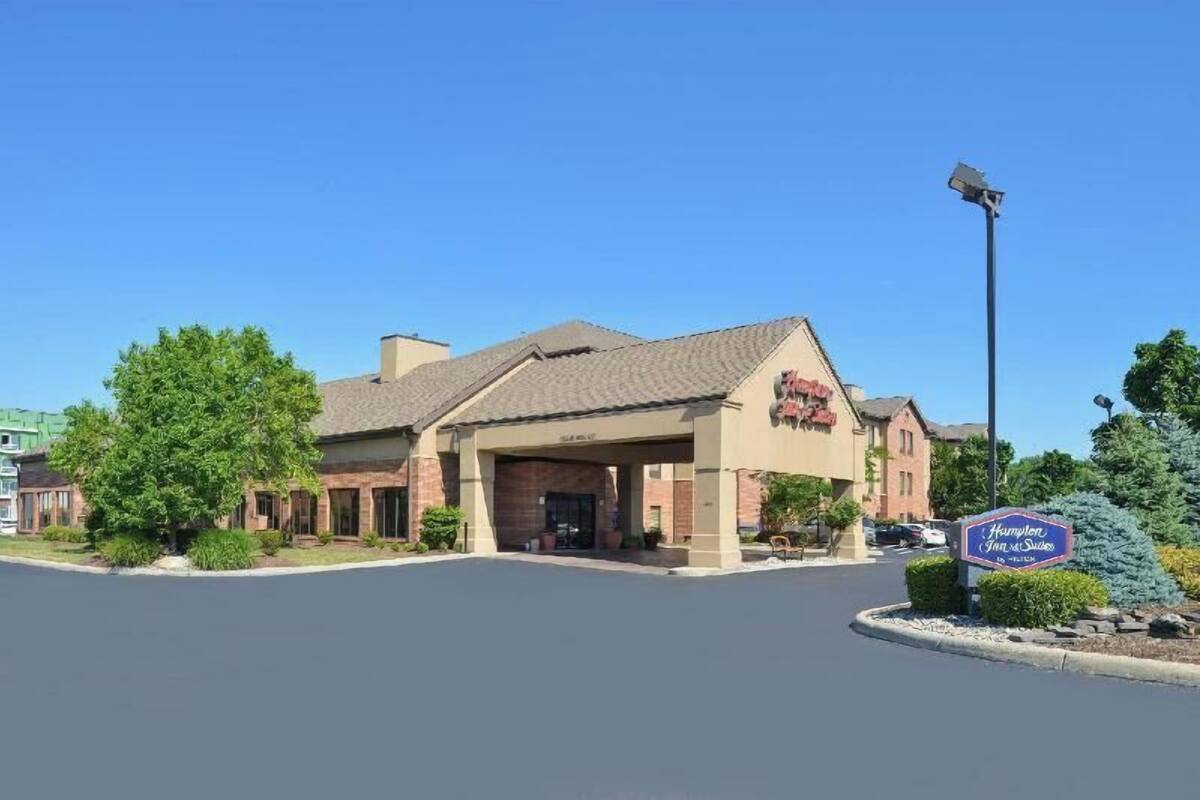 Un hotel Hampton Inn & Suites con fachada de ladrillo, entrada cubierta y estacionamiento.