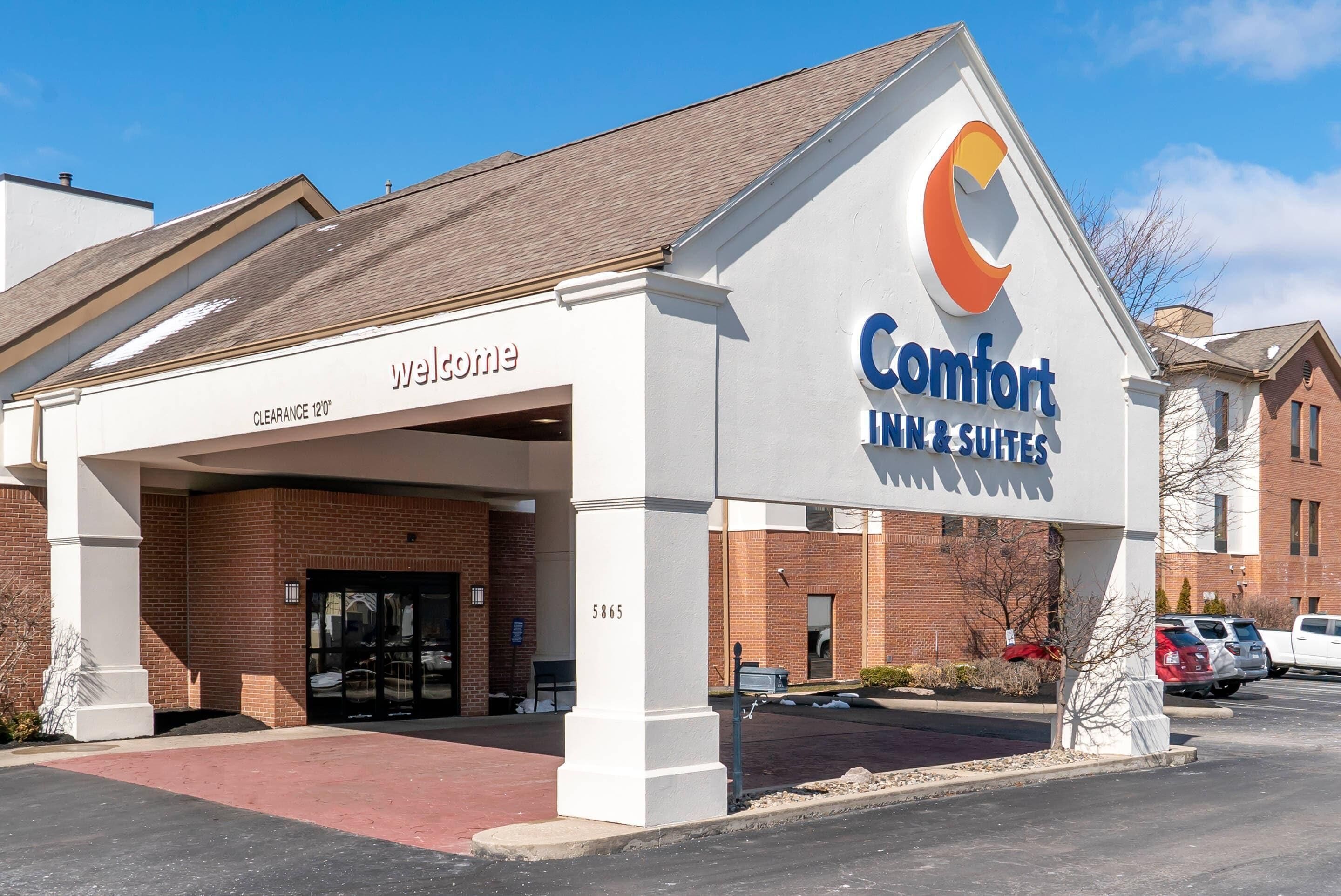 Un Comfort Inn & Suites con un letrero de 'Bienvenido' y un letrero que indica 'Altura libre 12'0'.