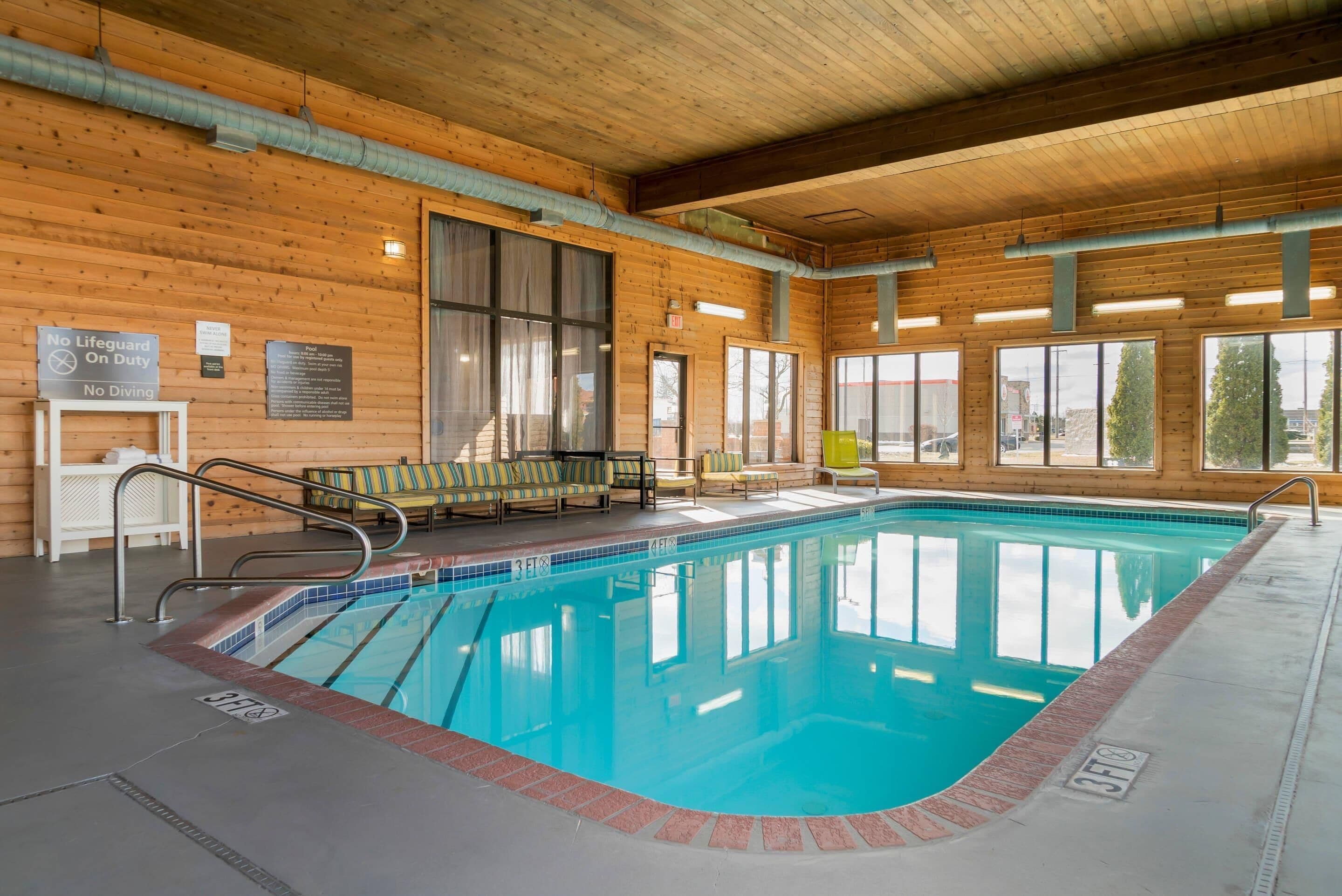 En indendørs swimmingpool med trævægge, et åbent område ved poolen og en bænk.