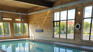 A pool area with wooden walls, large windows, and a caution sign on the floor.