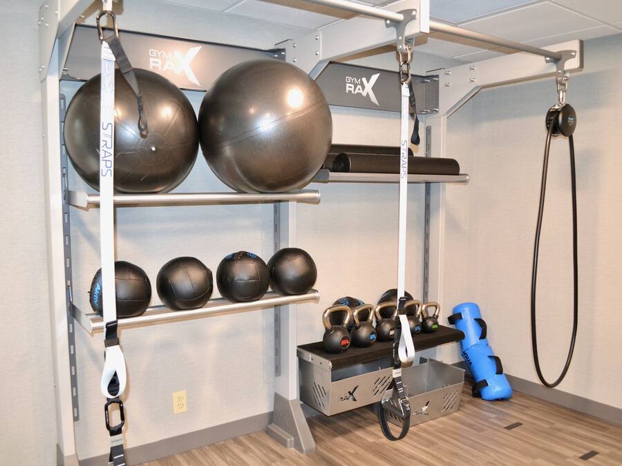 A gym with exercise equipment including medicine balls, kettlebells, and a pull-up bar.